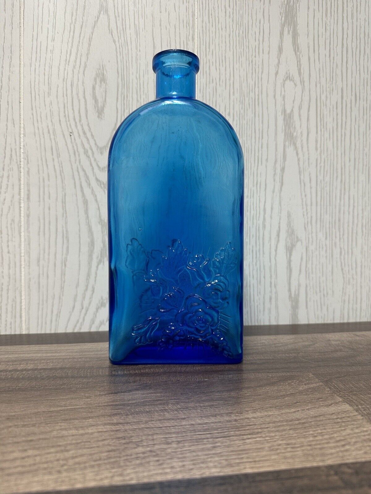 Vintage blue glass bottle with embossed flowers 