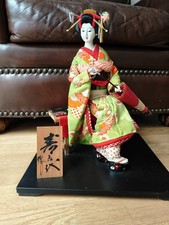 Very Beautiful Japanese Geisha Doll Dressed In Kimono Sitting On A Bench picture