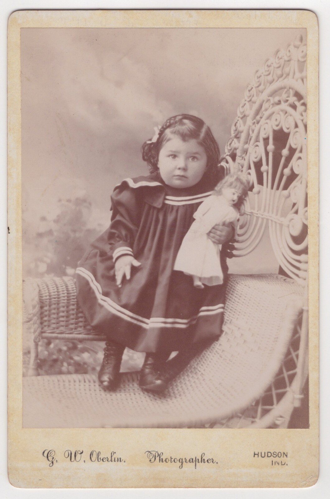 SWEET LITTLE GIRL HOLDING HER DOLL :WICKER CHAIR: HUDSON, INDIANA : CABINET CARD