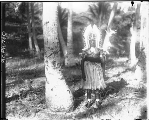 Queensland PNG Man in a leaf skirt and headdress, standing next to - Old Photo