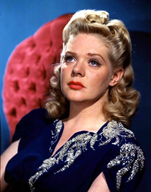US screen star Alice Faye wearing a smart blue top whilst sitting - 1953 Photo