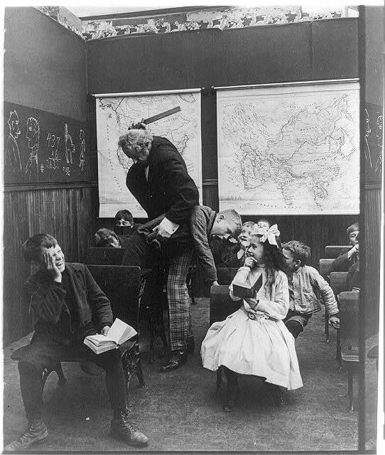 Teacher spanking small boy with ruler in classroom, posed scene Old Photo