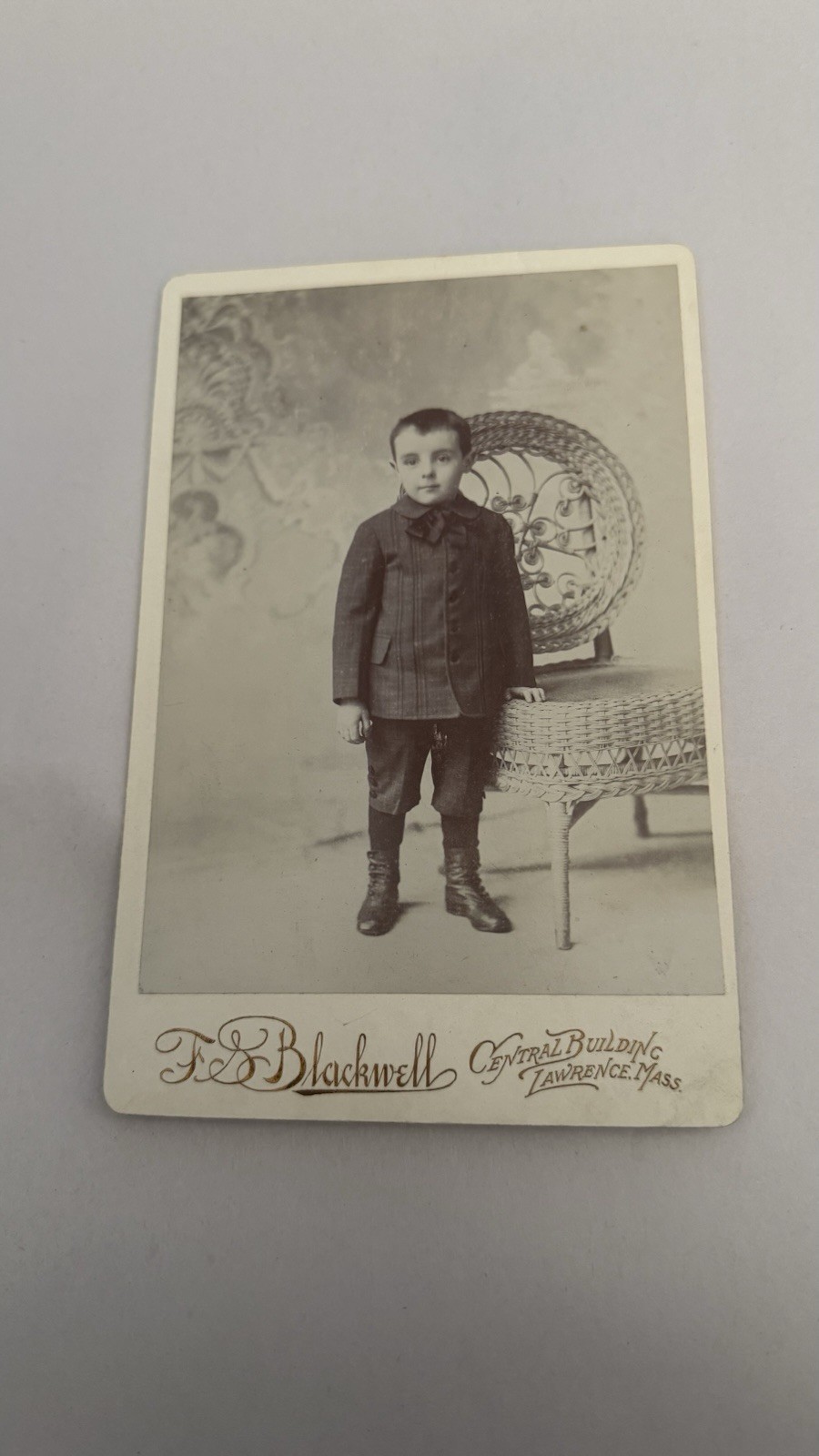 Little Boy In A Suit Standing Next To A Chair Antique Cabinet Photo