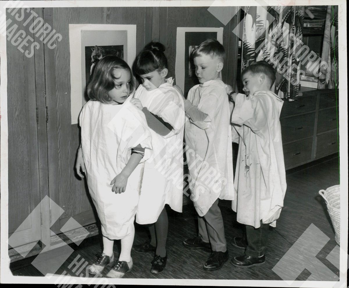 1968 Four children in paint smocks at a kindergarten classroom