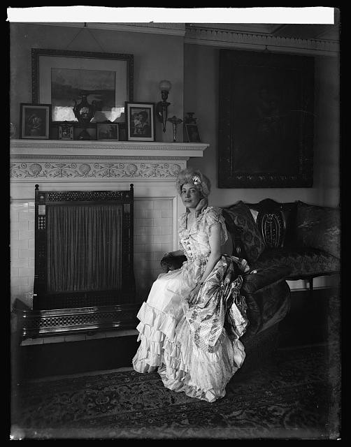 Photo:Eliz Howry 1919 1920 Woman in Victorian Dress by Fireplace