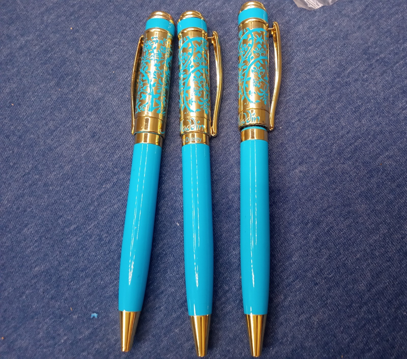 (Lot of 13) Disney *Aladdin* ballpoint pen in gold-tone metal and blue enamel.