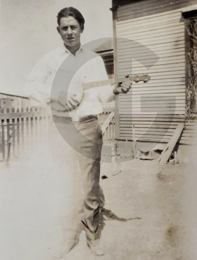 Man Playing a Banjo by a Farm Building: 1920\'s Snapshot Photo