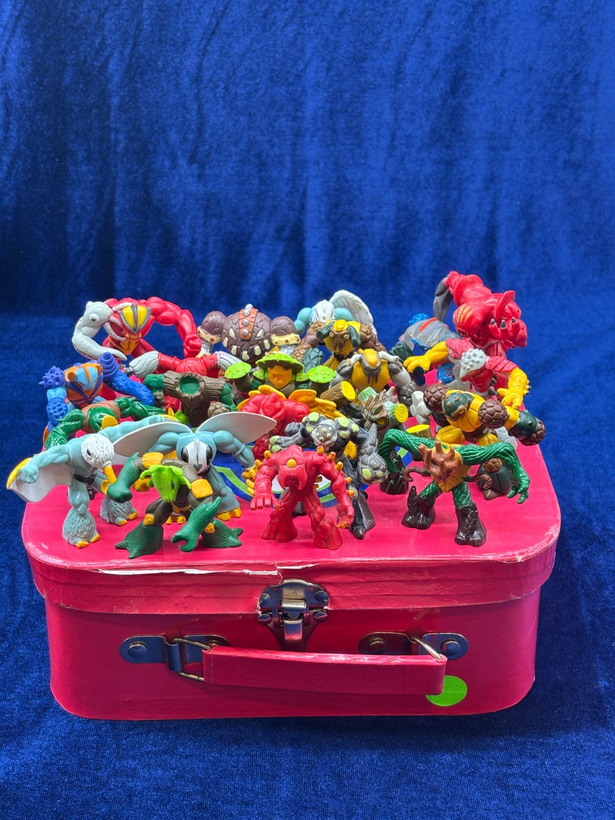 A Collection Of Various Gormiti Figurines Packed In A Pink Suitcase