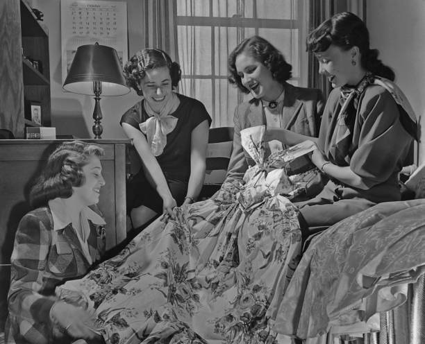 Four young women looking at a dress in a bedroom in October 1947 Old Photo