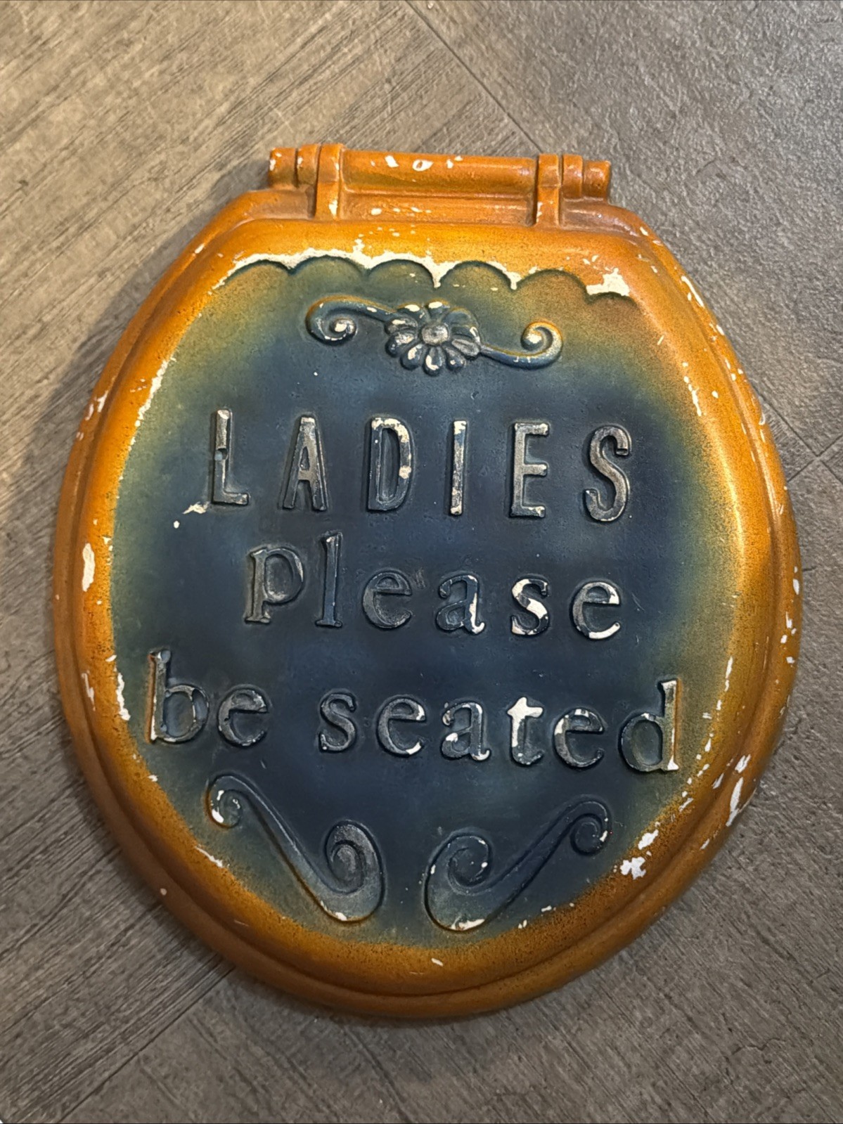 Vintage ceramic sign with the phrase 'Ladies Please be seated' embossed on it.